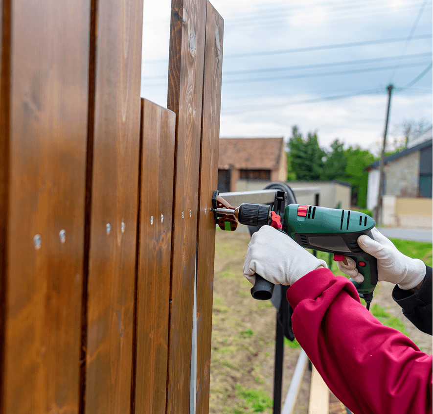 Person using drill on wooden fence
